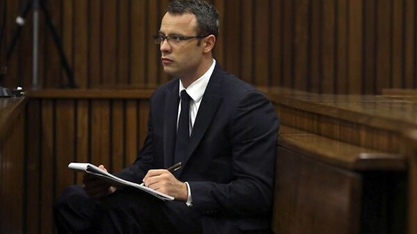 Olympic and Paralympic track star Oscar Pistorius takes notes during court proceedings at the North Gauteng High Court in Pretoria March 13, 2014.