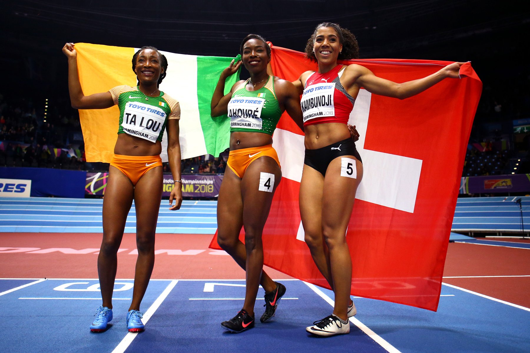 Murielle Ahoure (C) Marie-Josee Ta Lou (L) of Cote D'Ivoire and Mujinga Kambundji of Switzerland celebrates after the 60 Metres Womens Final during the IAAF World Indoor Championships on Day Two at Arena Birmingham on March 2, 2018 in Birmingham, England. Photo by Michael Steele/Getty Images for IAAF