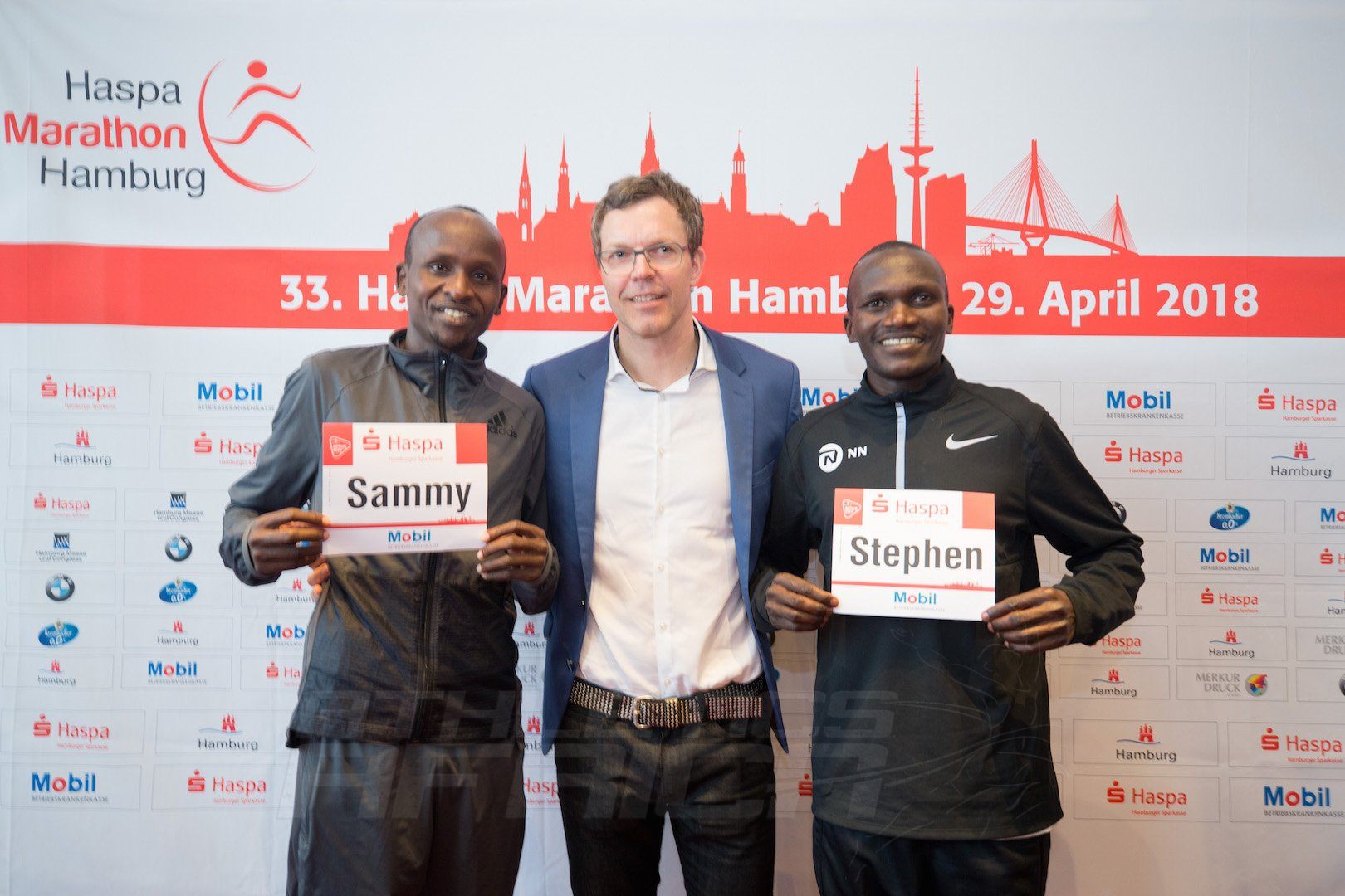 Kenyan Sammy Kitwara and Ugandan Stephen Kiprotich together with chief organiser Frank Thaleiser during the press conference in Hamburg. Photo Credit: HochZwei / Haspa Marathon Hamburg