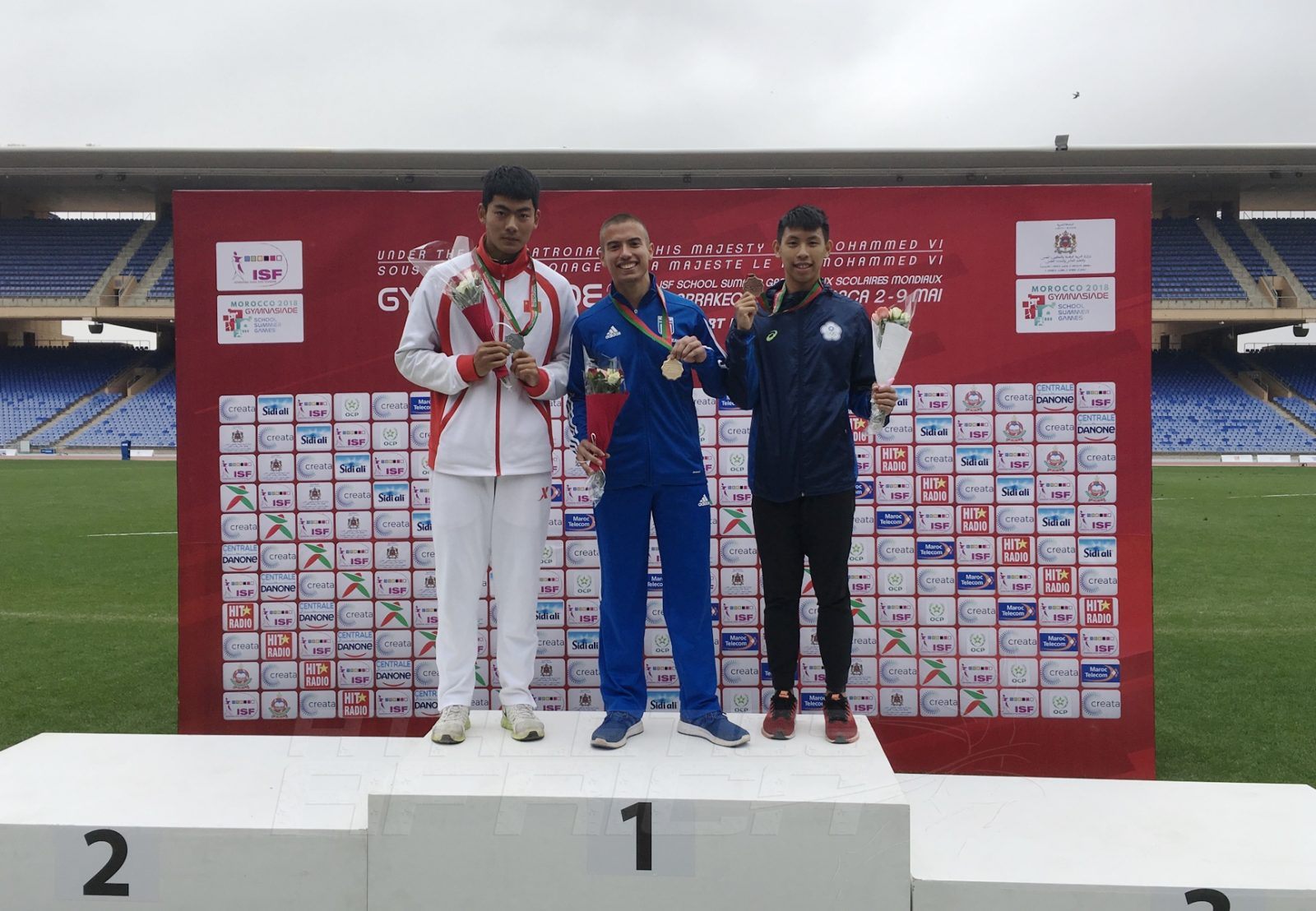 Ioannis Granitsiotis of Greece (C) flanked by Tai An of China and Yu-Sian Lin of Chinese Taipei on the podium after the Boys 100m medal presentation at Gymnasiade 2018 in Marrakech / Photo Credit: Yomi Omogbeja