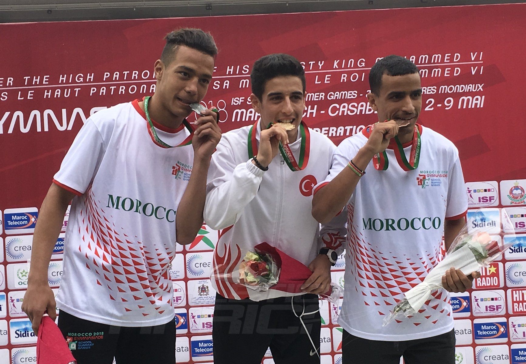 Turkey's Mehmet Celik (C) flanked by Moroccans Mohammed Aboutahiry and Yeva Podhorodetska on the podium after the Boys 800m medal presentation at Gymnasiade 2018 in Marrakech / Photo Credit: Yomi Omogbeja