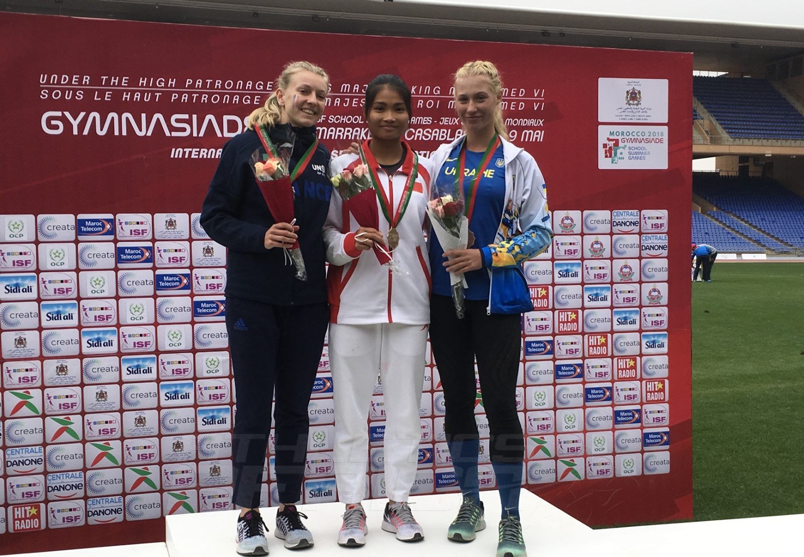 China's He Li (C) flanked by Marie Ange Rimlinger of France and Yeva Podhorodetska of Ukraine on the podium after the Girls 100m medal presentation at Gymnasiade 2018 in Marrakech / Photo Credit: Yomi Omogbeja