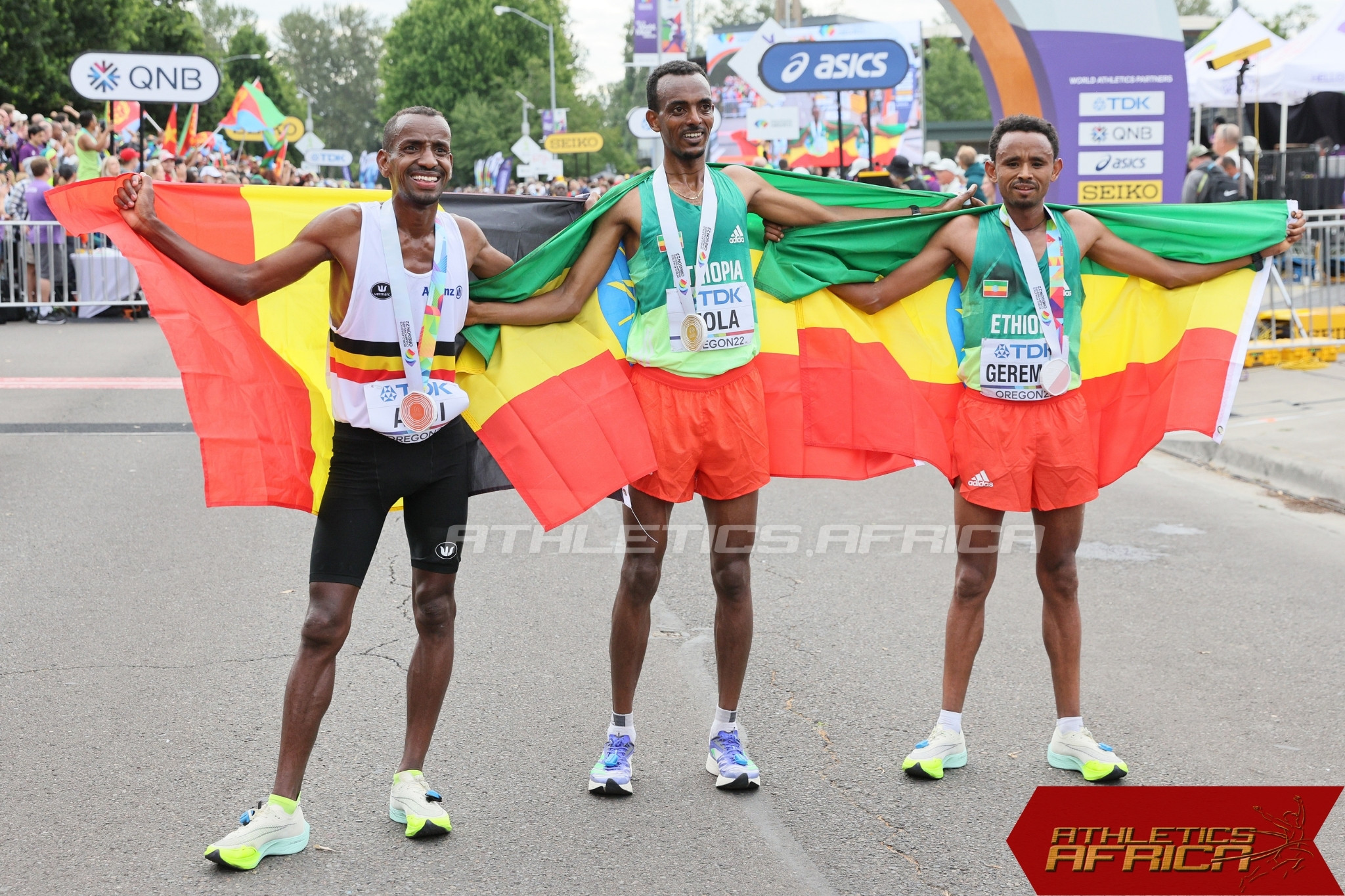 Ethiopia's Tamirat Tola flanked by compatriot Mosinet Geremew and Bashir Abdi on the podium after the men's marathon final / Photo credit: Getty Images for World Athletics