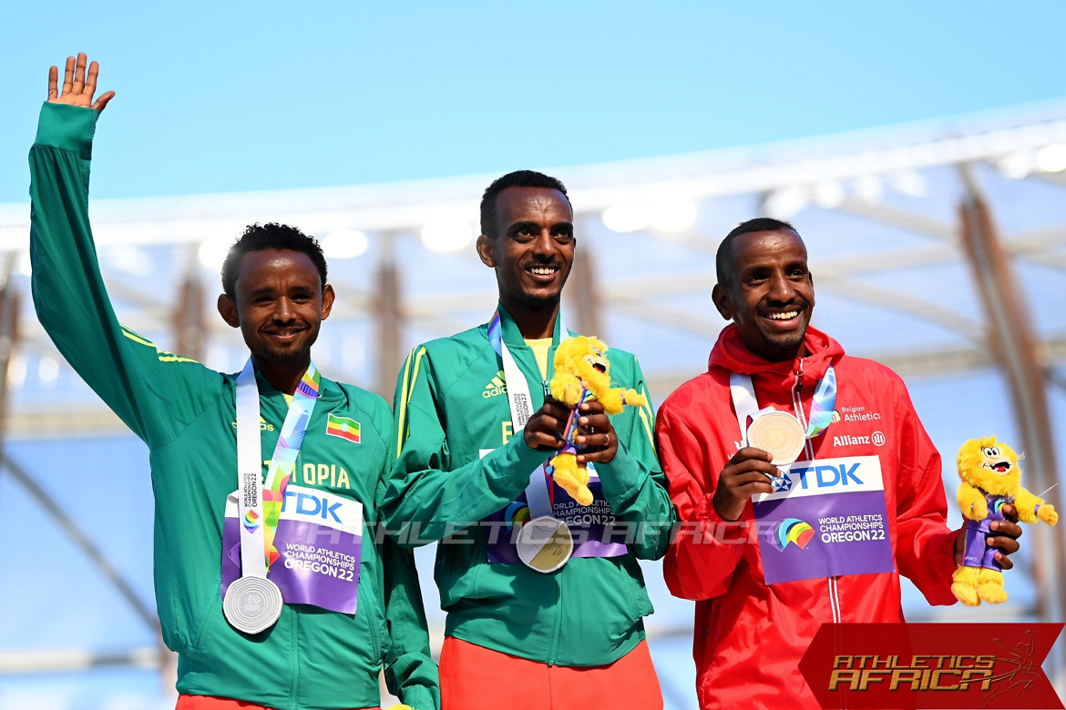 Ethiopia's Tamirat Tola flanked by compatriot Mosinet Geremew and Bashir Abdi on the podium for the men's marathon medal ceremony / Photo credit: Getty Images for World Athletics